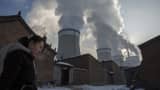 A Chinese resident walks out of her house her house next to a coal fired power plant on November 26, 2015 in Shanxi, China.