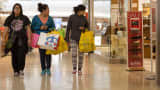Shoppers carry bags while walking through the Cherry Creek Shopping Center in Denver.