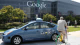 A bicyclist rides by a Google self-driving car at the Google headquarters.