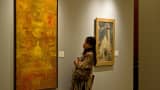 A visitor looks at an untitled painting (L) by Vasudeo S. Gaitonde