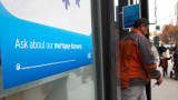 A man exits a Citibank branch with window advertising for mortgages, in New York.