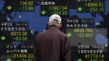 A pedestrian looks at an electronic board showing the stock market indices of various countries outside a brokerage in Tokyo, Japan, January 7, 2016.