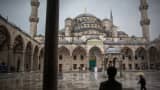 Tourists hold umbrellas to shelter from the rain in the central square inside the Blue Mosque, also known as the Sultan Ahmed, in Istanbul, Turkey, on Friday, June 14, 2013
