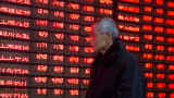 An investor walks past an electronic screen showing stock information at a brokerage house in Nanjing, Jiangsu province, January 19, 2016.