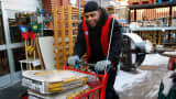 Employee Donald Mills wheels out bags of sand for a customer at Strosniders Hardware store in Silver Spring, Md., Jan. 21, 2016.