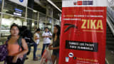 Travelers walk past a poster with information about the Zika virus during a campaign by Peru's Health Ministry at Plaza Norte bus station in Lima, Peru, on Feb. 4, 2016.