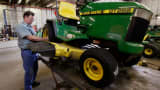 A man works on a customer's John Deere lawn tractor at the Buck Bros. dealership in Hampshire, Illinois.