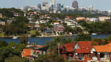 Houses stand by the waterfront as commercial buildings stand in the distance in Sydney, Australia, on Wednesday, Feb. 17, 2016.