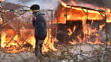 A migrant walks past shacks burning during the dismantling of half of the 'Jungle' migrant camp in the French northern port city of Calais, on February 29, 2016. Clashes broke out between French riot police and migrants on February 29 as bulldozers moved into the grim shantytown on the edge of Calais known as the 'Jungle' to start destroying hundreds of makeshift shelters.