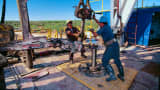 Oil workers moving a drill on a rig in Texas.