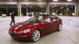 A man walks past a Tesla Model S electric vehicle in the Tesla Motors auto plant in Fremont, California.