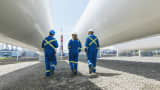 Workers walking along tanks at gas plant