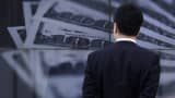 A businessman looks at a screen displaying a photo of U.S. $100 bank notes in Tokyo.