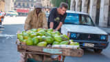 Cuban fruit and vegetable sellers push a handcart of avocados for sale in downtown Havana, Cuba.