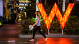 A woman walks past signage displayed outside of the W Hotel Hollywood in Hollywood, California.