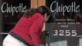A woman looks through the locked front door of the Chipolte Restaurant in Washington, D.C.