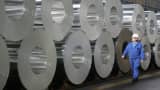 A worker walks among rolls of semi-finished aluminum at an Alcoa aluminum factory.