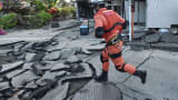 A member of a rescue team runs on a street cracked by the earthquake in Mashiki, Kumamoto prefecture on April 16, 2016.