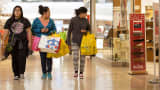 Shoppers carry bags while walking through the Cherry Creek Shopping Center in Denver.