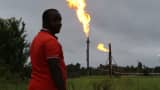 A man looks on as flares burn from pipes at an oil flow station in Idu, Rivers State, Nigeria.