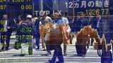 Pedestrians are reflected on an electronic stock quotation board at the window of a securities company in Tokyo on May 12, 2016.