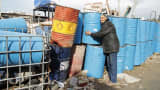 A man stacks discarded oil barrels at a scrap metal yard in Tunis.