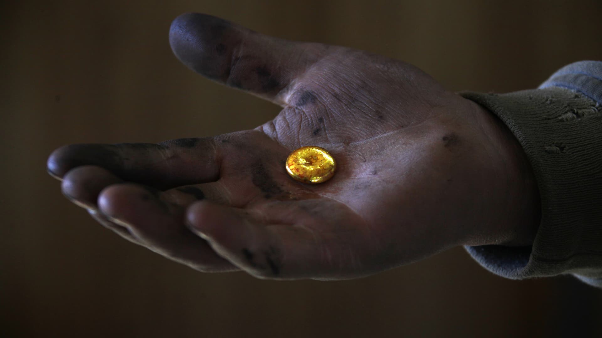 A small-scale miner holds his gold that was melted together at a processing plant located around 100km (62 miles) north of the Mongolian capital city Ulan Bator .