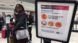 A woman looks at a Center for Disease Control (CDC) health advisory sign about the dangers of the Zika virus as she lines up for a security screening at Miami International Airport in Miami, Florida.