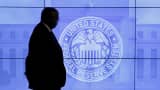 A security guard walks in front of an image of the Federal Reserve in Washington, D.C.