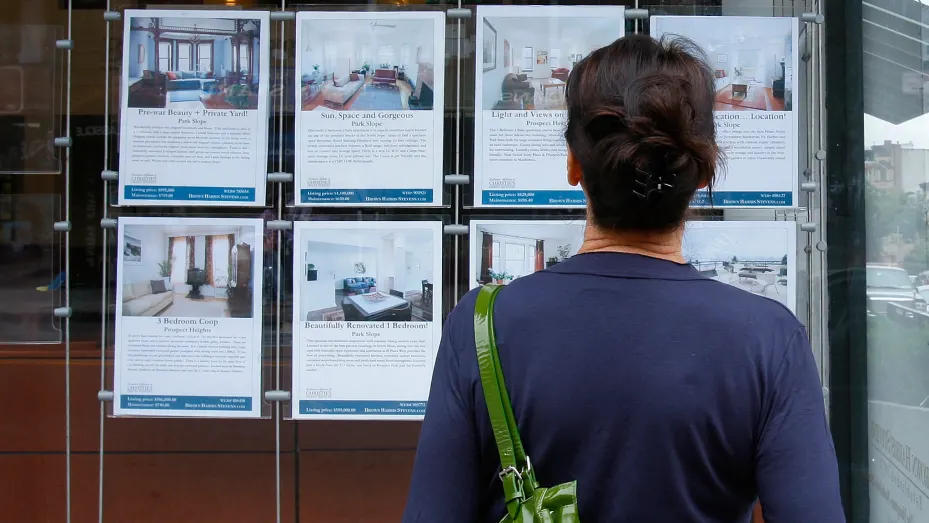 A customer looks at listings on display outside a Brown Harris Stevens offices in New York.