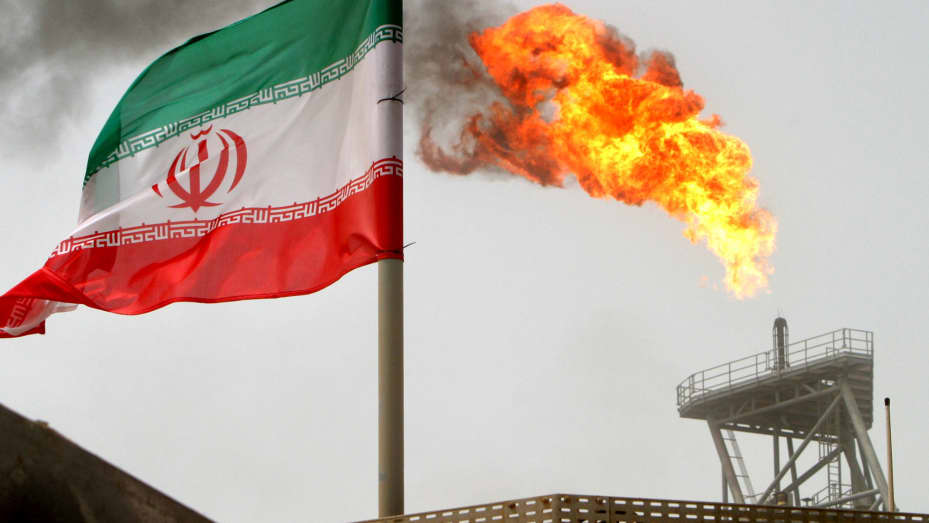 A gas flare on an oil production platform is seen alongside an Iranian flag in the Gulf.