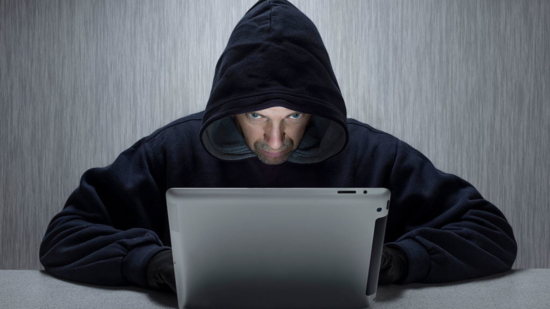 A hooded man representing a cyber criminal.