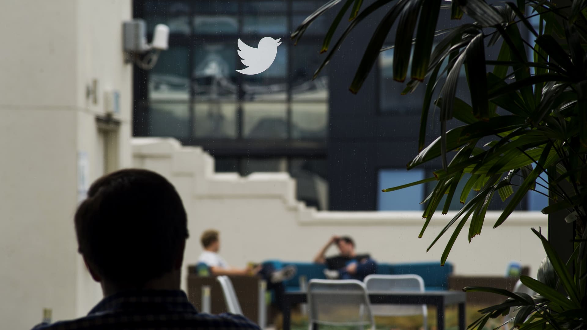 The silhouette of an employee is seen beneath the Twitter Inc. logo