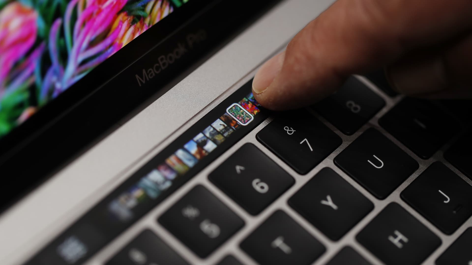 An Apple employee points to the Touch Bar on a new Apple MacBook Pro laptop