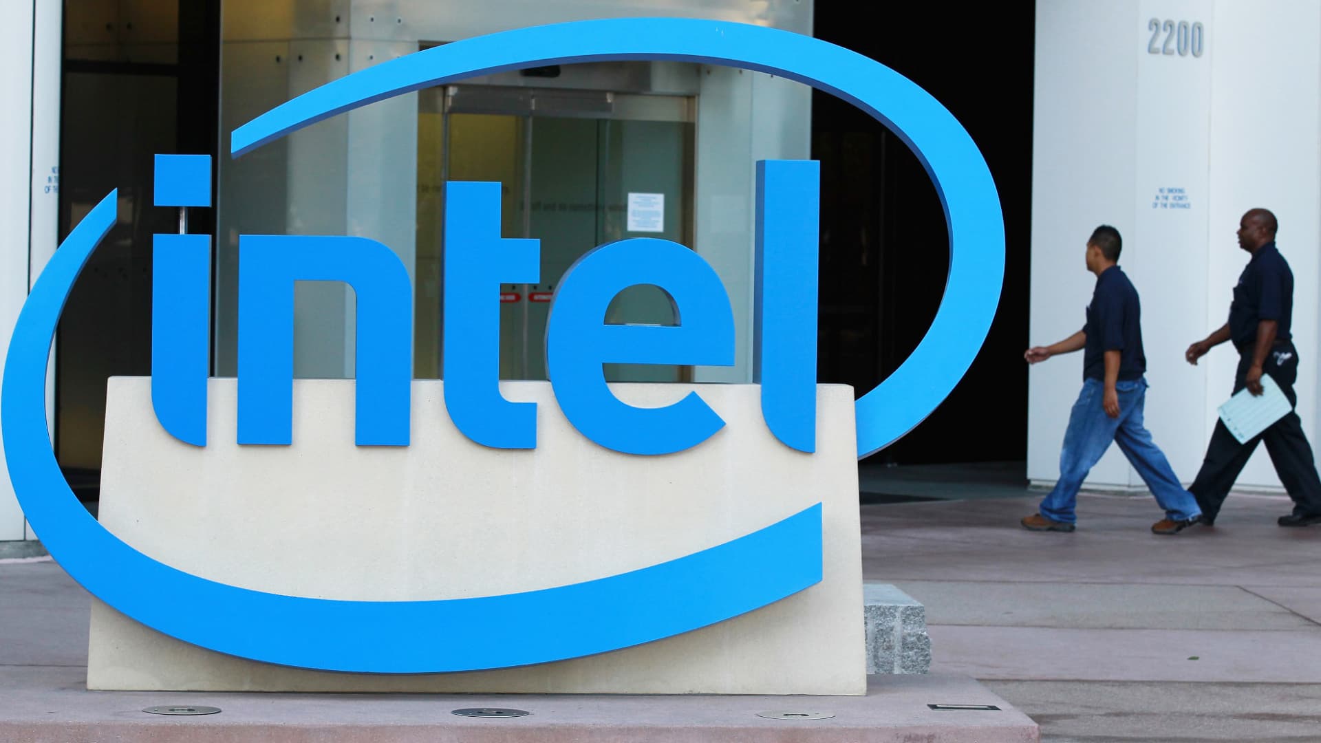 Intel employees walk by a sign as they enter their office in Santa Clara, California.