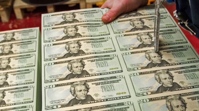 Un periodista recoge una pila de hojas sin cortar de billetes de 20 dólares estadounidenses el 12 de julio de 2012 en la Oficina de Grabado de Estados Unidos en Washington, DC.