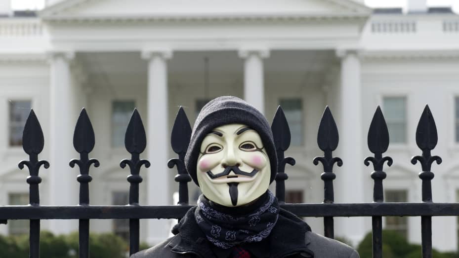 A person standing outside the White House wearing a Guy Fawkes mask as part of a 2013 protest featuring supporters of the hacking group Anonymous.