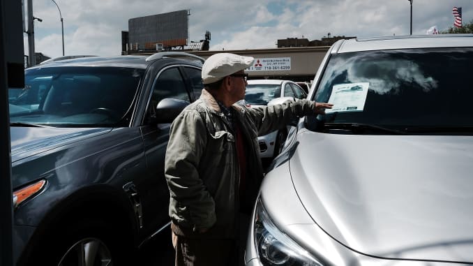 GS: A man looks at cars for sale at an auto dealership in New York City.