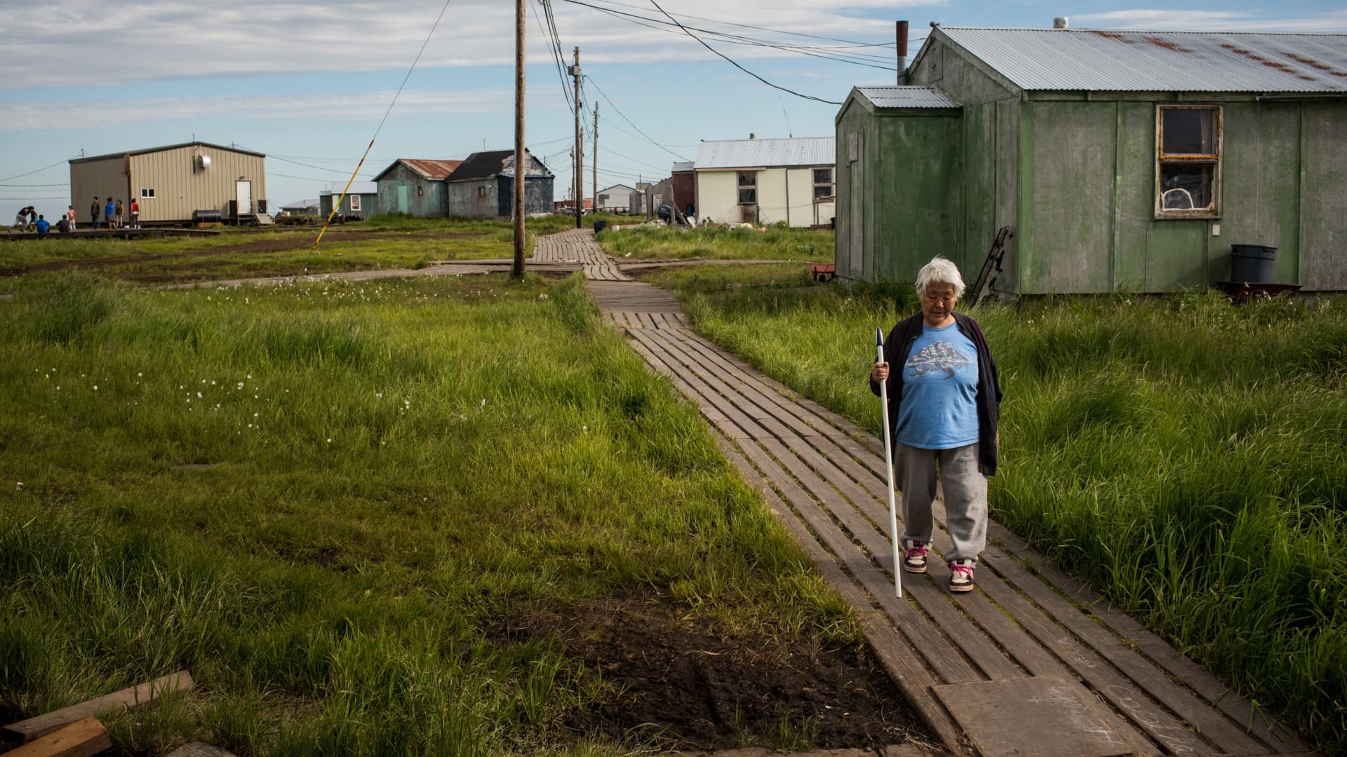A resident walks down a wooden sidewalk in Newtok, Alaska.