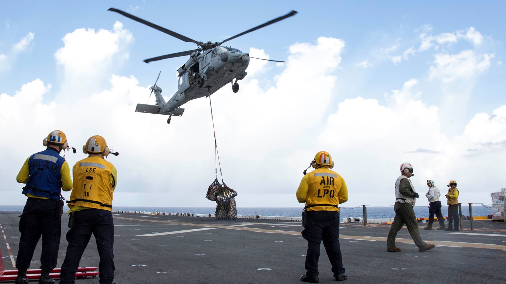 Sailors aboard the amphibious assault ship USS Kearsarge (LHD 3) observe as an MH-60 Sea Hawk helicopter drops pallets of supplies onto the flight deck during a replenishment-at-sea with the fast combat support ship USNS Supply (T-AOE 6) for relief efforts in the aftermath of Hurricane Maria in Puerto Rico on September 28, 2017.