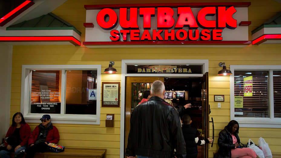 Customers enter a Bloomin' Brands' Outback Steakhouse restaurant at the Queens Place Mall in the Queens borough of New York.