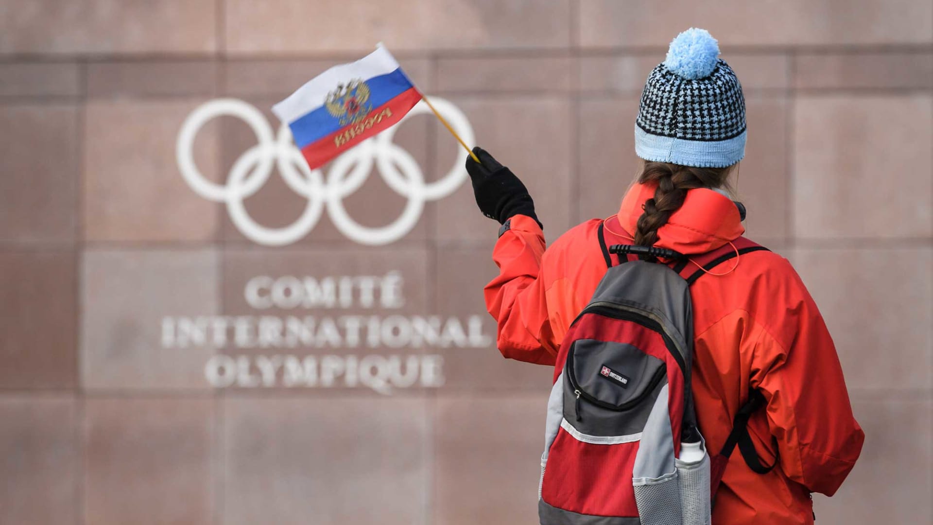 A supporter waves a Russian flag in front of the logo of the International Olympic Committee (IOC) at their headquarters on December 5, 2017 in Pully near Lausanne, Switzerland.