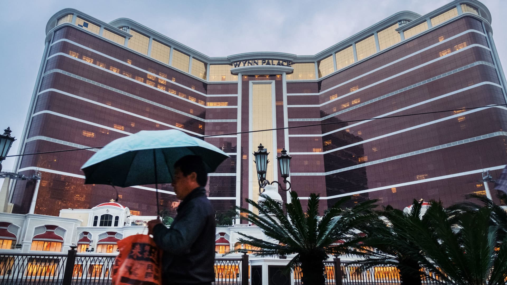 A pedestrian with an umbrella walks in front of the Wynn Palace casino resort, operated by Wynn Resorts Ltd., in Macau, China, Jan. 31, 2018.