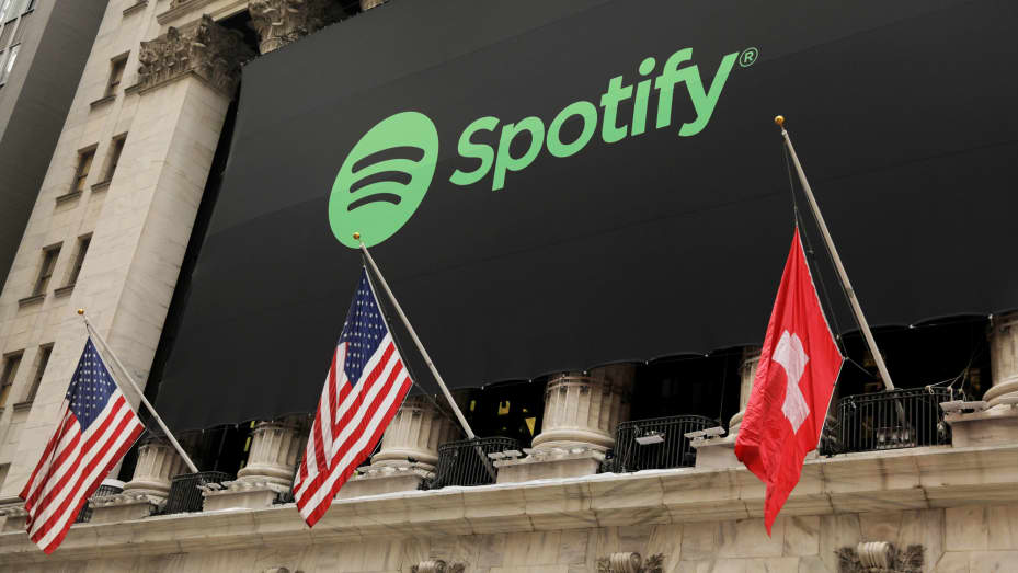 El logotipo de Spotify cuelga en la fachada de la Bolsa de Valores de Nueva York con una bandera de EE. UU. y Suiza mientras la empresa cotiza sus acciones con una cotización directa en Nueva York, el 3 de abril de 2018.