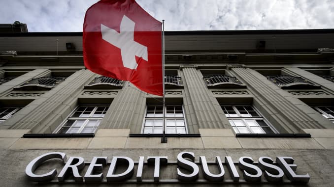 A Swiss flag flies over a sign of Credit Suisse in Bern, Switzerland
