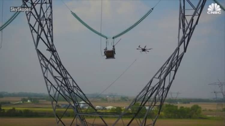 Watch these drones string power lines on poles high above the ground