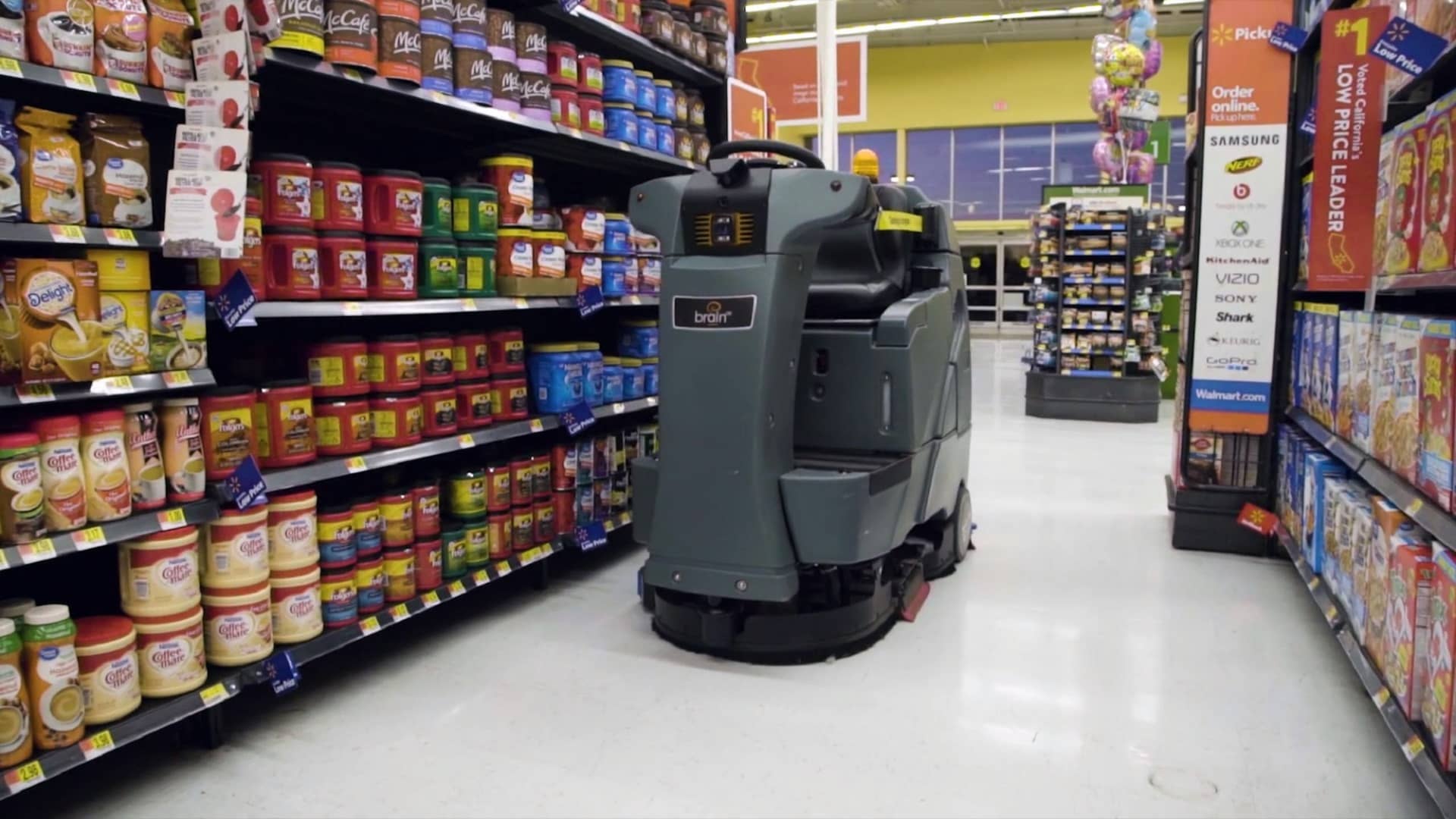 A Brain Corp. autonomous floor scrubber, called an Auto-C, cleans the aisle of a Walmart's store. Sam's Club completed the rollout of roughly 600 specialized scrubbers with inventory scan towers last October in a partnership Brain Corp.
