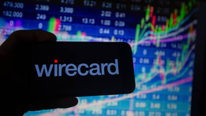 Logo của Wirecard có thể được nhìn thấy trên một điện thoại thông minh được đặt trước biểu đồ thị trường chứng khoán.