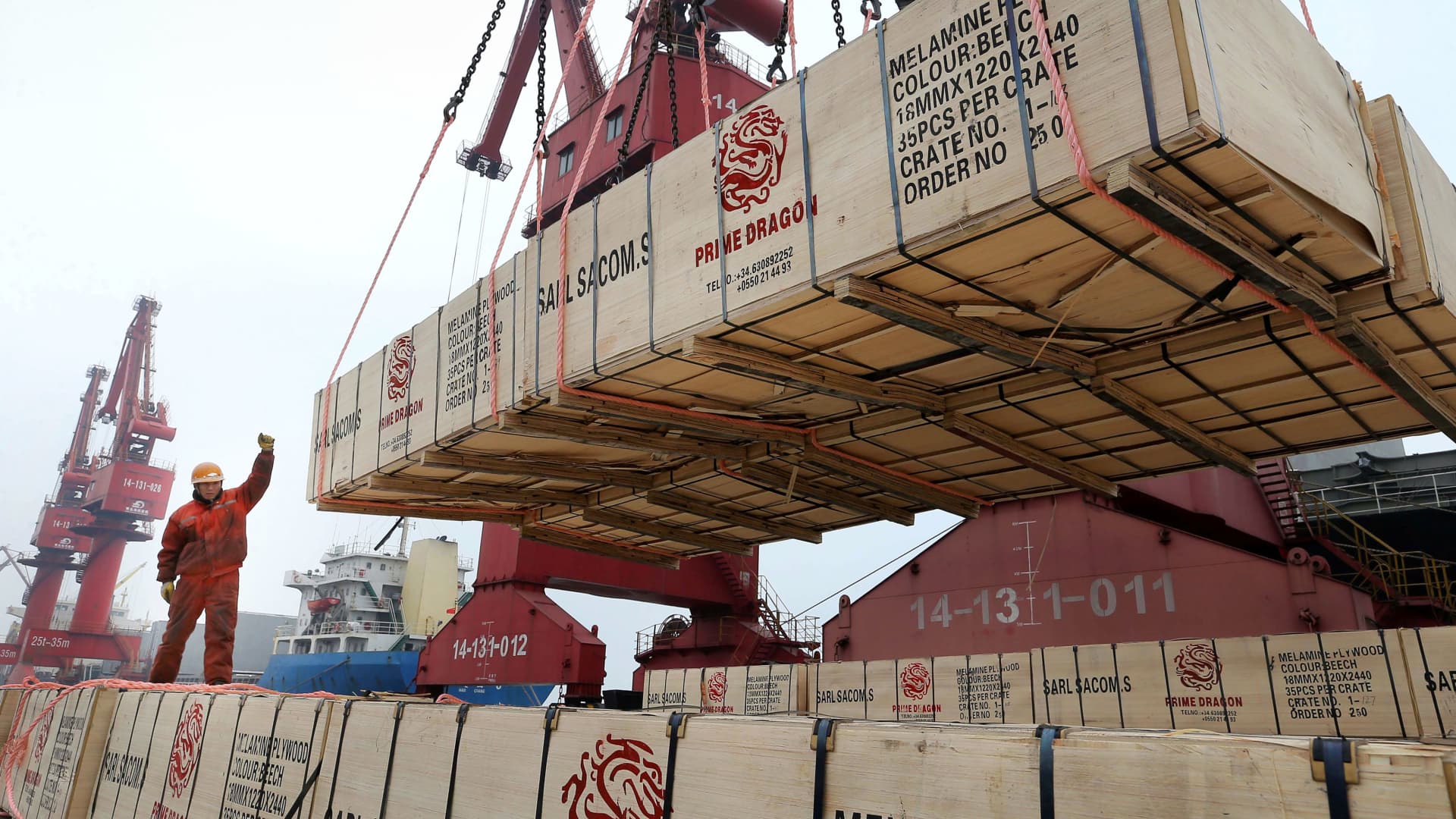 A worker gestures as a crane lifts goods for export onto a cargo vessel at a port in Lianyungang, China, February 13, 2019.