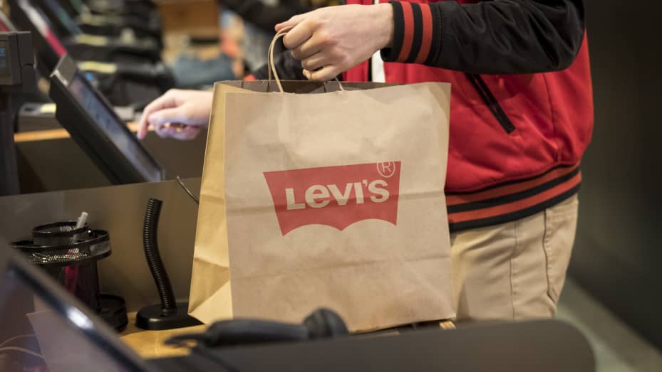An employee holds a shopping bag while ringing up a customer at the Levi Strauss & Co. flagship store in San Francisco, March 18, 2019.